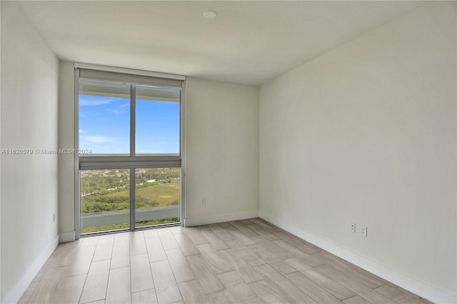 unfurnished room with light wood-type flooring and floor to ceiling windows