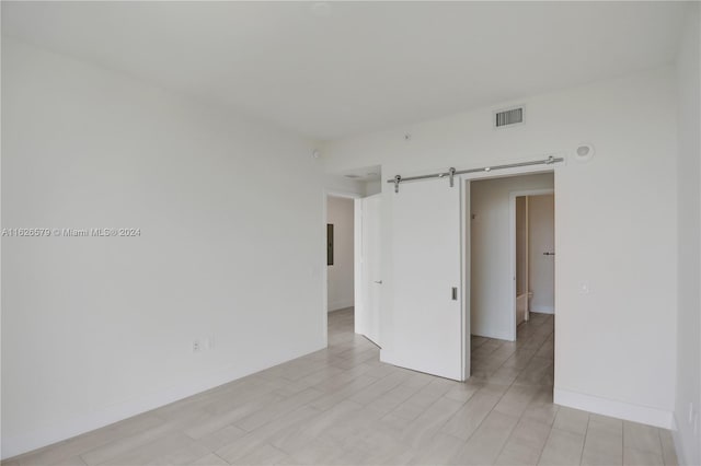 empty room featuring light wood-type flooring and a barn door