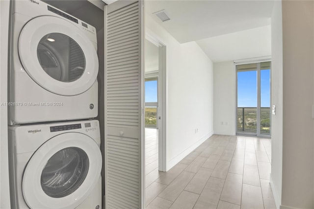 clothes washing area with stacked washer and dryer and light tile patterned flooring