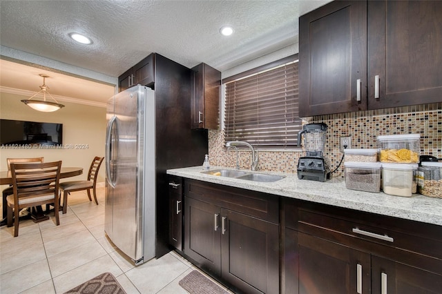 kitchen with crown molding, sink, light stone countertops, tasteful backsplash, and stainless steel refrigerator