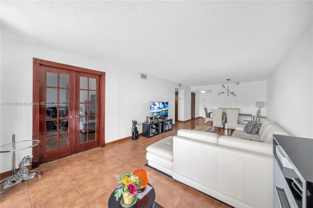 tiled living room with french doors and a textured ceiling