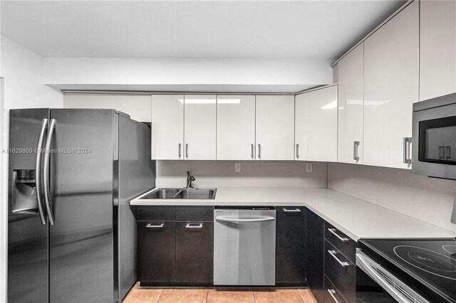 kitchen featuring appliances with stainless steel finishes, light tile patterned flooring, white cabinets, and sink