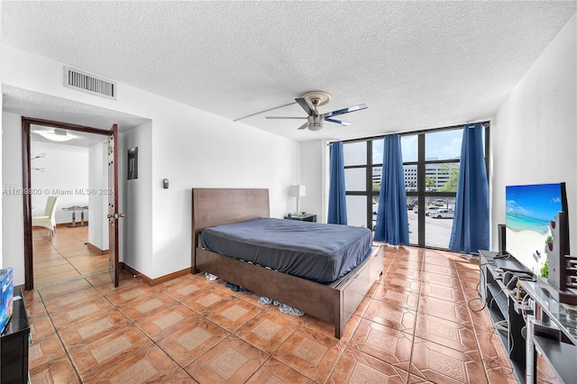 bedroom featuring ceiling fan, tile patterned floors, floor to ceiling windows, and a textured ceiling