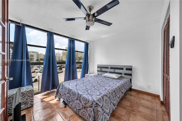 bedroom featuring floor to ceiling windows, ceiling fan, a textured ceiling, and a closet