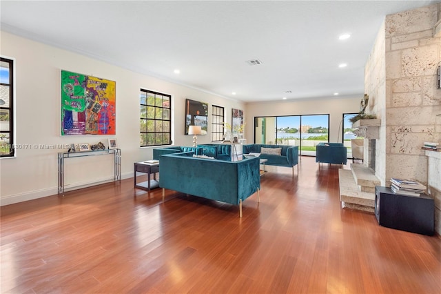 living room featuring a fireplace, crown molding, and hardwood / wood-style floors