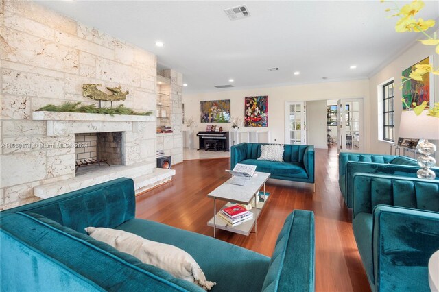 living room with french doors, a stone fireplace, dark hardwood / wood-style floors, and crown molding