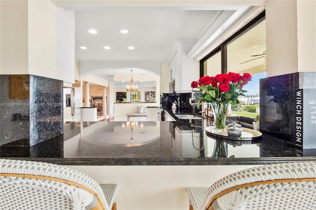 kitchen featuring sink, white cabinetry, a fireplace, and ceiling fan with notable chandelier