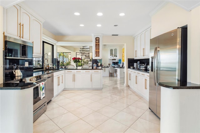 kitchen featuring white cabinets, backsplash, appliances with stainless steel finishes, and kitchen peninsula