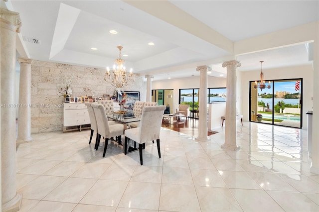 dining area featuring light tile patterned flooring, a notable chandelier, decorative columns, a tray ceiling, and tile walls