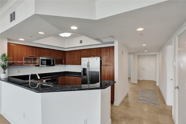 kitchen featuring kitchen peninsula, stainless steel appliances, dark stone counters, and sink