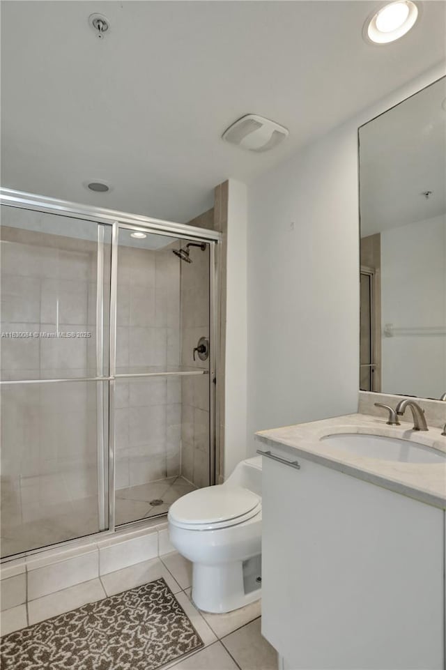 bathroom featuring toilet, vanity, tile patterned floors, and a shower with shower door