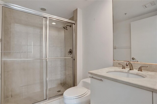 bathroom with a shower with door, vanity, and toilet