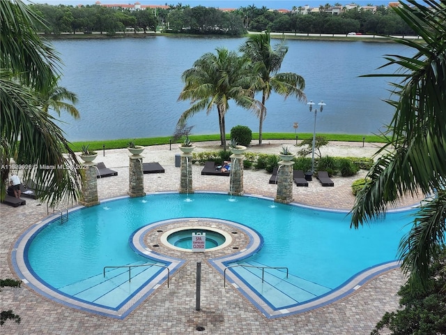 view of swimming pool with a patio, a water view, pool water feature, and a hot tub