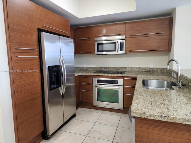 kitchen featuring light tile patterned floors, light stone counters, appliances with stainless steel finishes, and sink