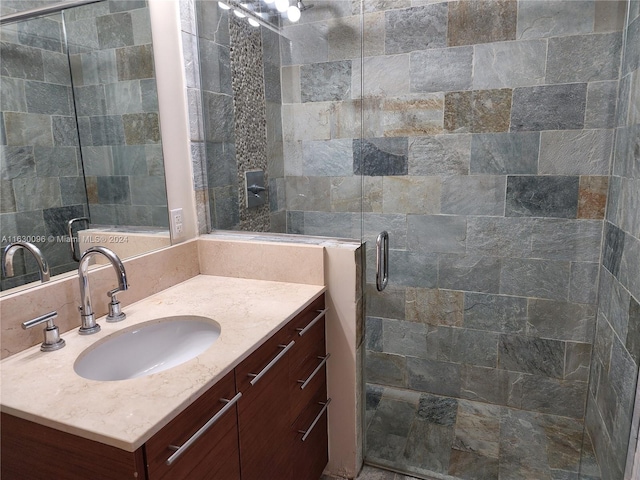 bathroom featuring a shower with shower door and vanity