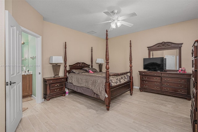 bedroom with ceiling fan, ensuite bathroom, a textured ceiling, and light hardwood / wood-style floors