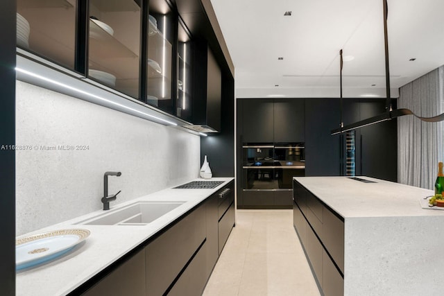 kitchen featuring a center island, sink, stovetop, pendant lighting, and light tile patterned floors