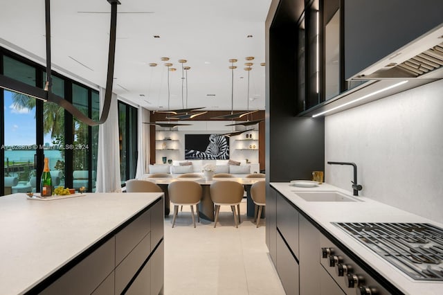 kitchen with sink, decorative light fixtures, range hood, stainless steel gas stovetop, and light tile patterned flooring