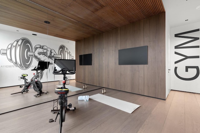 workout area with light hardwood / wood-style flooring, wooden walls, and wood ceiling