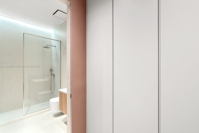 bathroom with a tile shower, vanity, and toilet