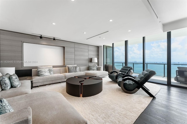 living room featuring a water view, floor to ceiling windows, track lighting, and hardwood / wood-style floors