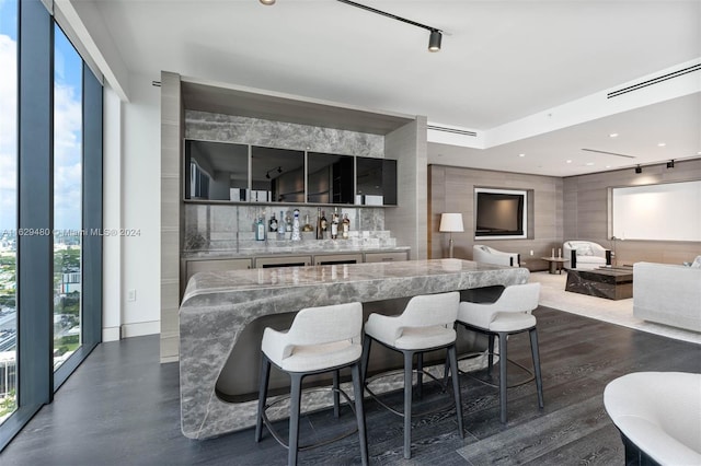 kitchen with a breakfast bar area, tasteful backsplash, rail lighting, and light stone countertops