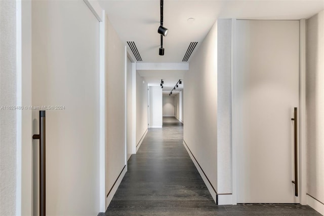 corridor with rail lighting and dark hardwood / wood-style floors