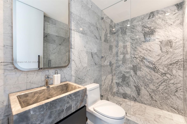 bathroom featuring vanity, toilet, a tile shower, and tile walls