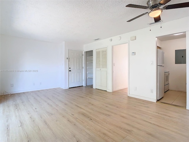 unfurnished bedroom featuring light wood-type flooring, a textured ceiling, electric panel, and refrigerator