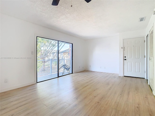 spare room featuring ceiling fan, light wood-type flooring, and a textured ceiling