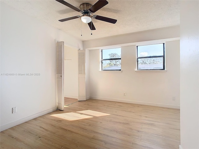 empty room with ceiling fan, light hardwood / wood-style floors, and a textured ceiling