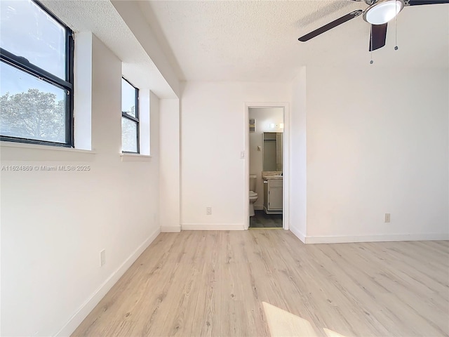 unfurnished room with ceiling fan, a textured ceiling, and light wood-type flooring