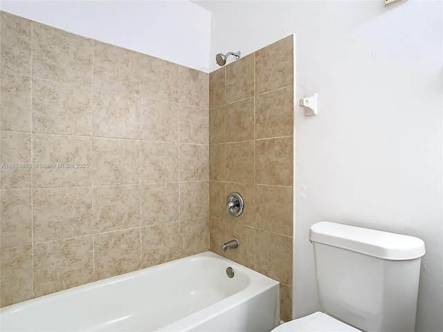 bathroom featuring tiled shower / bath combo and toilet