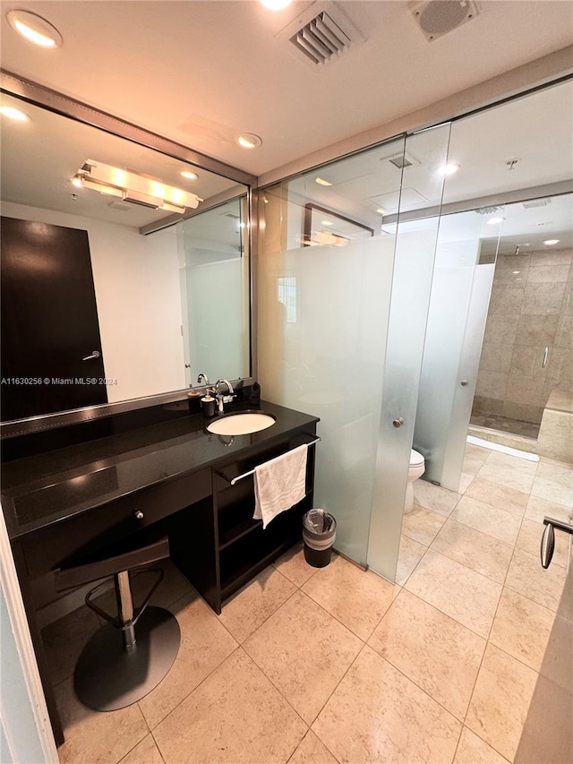 bathroom featuring vanity, tile patterned flooring, toilet, and a shower with door