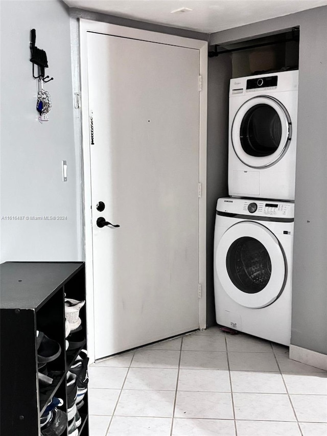 laundry area with light tile patterned flooring and stacked washer / drying machine