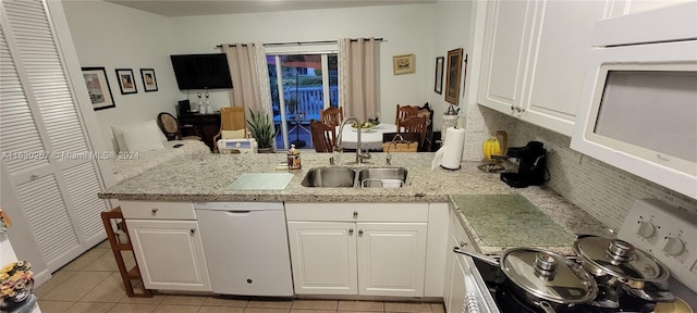 kitchen featuring tasteful backsplash, white appliances, kitchen peninsula, white cabinets, and sink