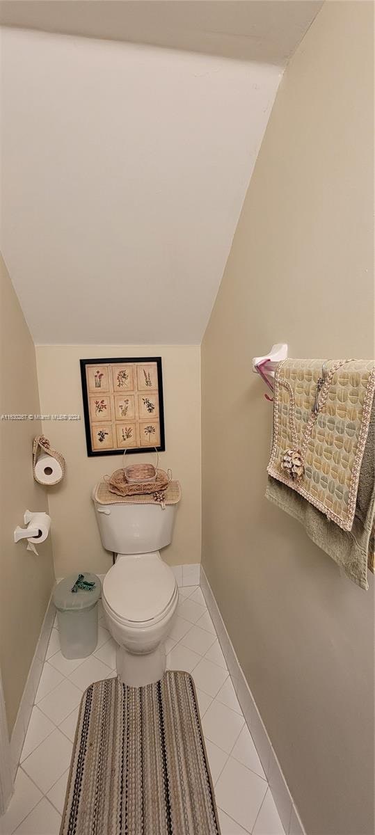 bathroom with lofted ceiling, tile patterned floors, and toilet