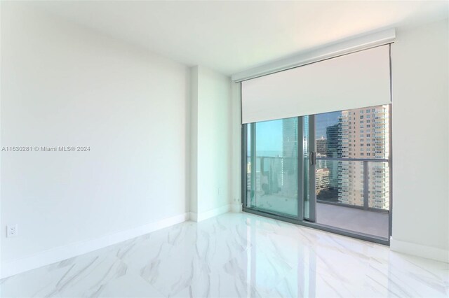 empty room with light tile patterned flooring and floor to ceiling windows