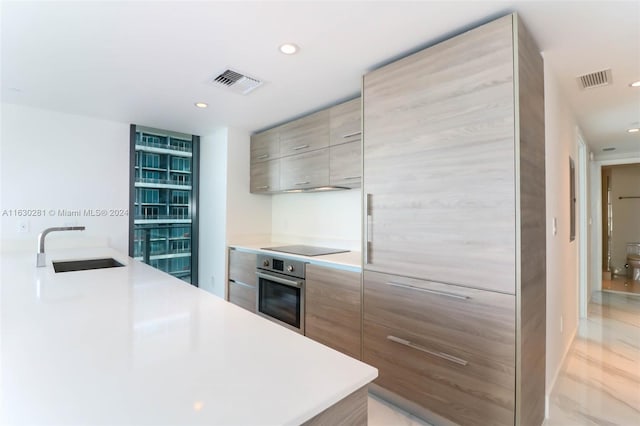 kitchen with black electric stovetop, sink, and stainless steel oven