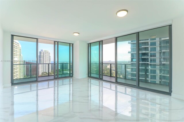 tiled spare room featuring a wall of windows and plenty of natural light