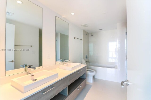 full bathroom with tiled shower / bath combo, tile patterned floors, double sink vanity, and toilet