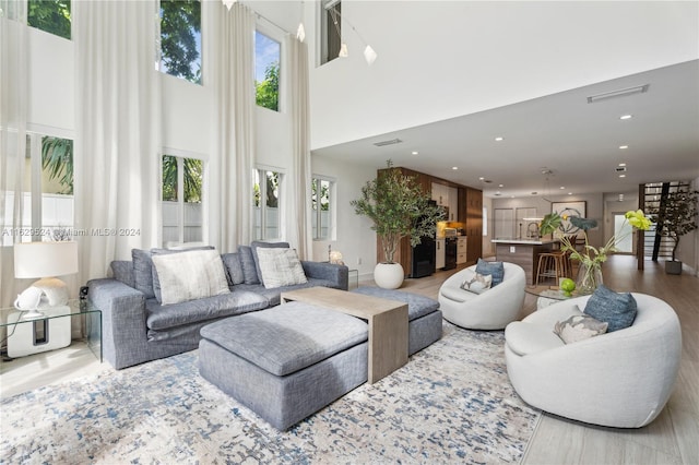 living room featuring a towering ceiling, wood-type flooring, and a wealth of natural light