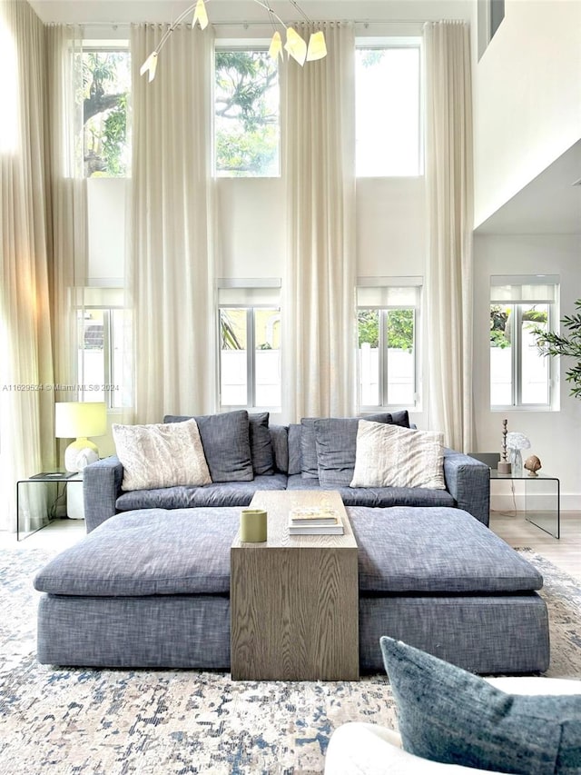 living room featuring a towering ceiling, wood-type flooring, and a wealth of natural light