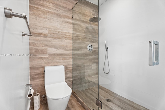 bathroom with toilet, a shower with shower door, and wood-type flooring