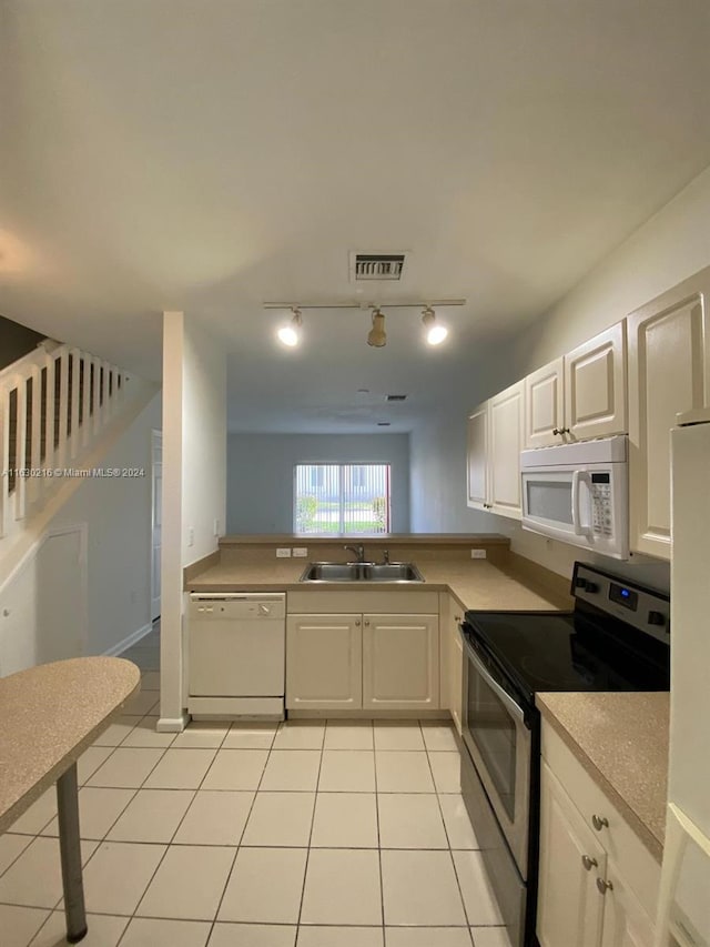 kitchen featuring sink, white appliances, light tile patterned floors, rail lighting, and white cabinets