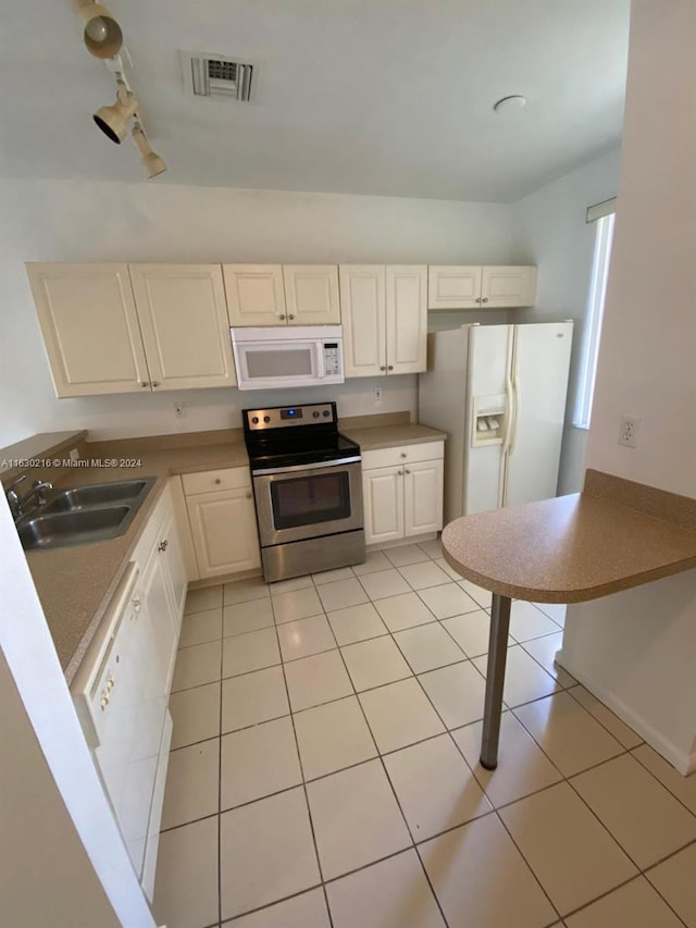 kitchen with sink, white appliances, light tile patterned floors, white cabinets, and kitchen peninsula