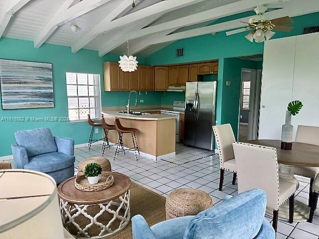 kitchen with vaulted ceiling with beams, light tile patterned floors, stainless steel fridge, and electric range