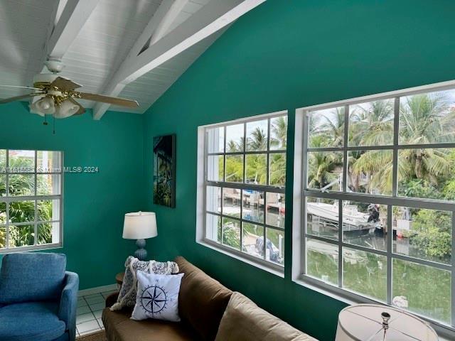 living area with lofted ceiling with beams, tile patterned flooring, and ceiling fan