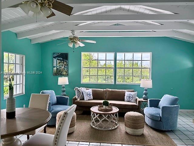 tiled living room featuring ceiling fan and vaulted ceiling with beams