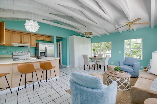 kitchen featuring sink, vaulted ceiling with beams, light tile patterned flooring, stainless steel fridge with ice dispenser, and ceiling fan with notable chandelier